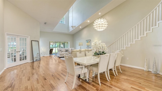 dining room with light wood-type flooring, visible vents, high vaulted ceiling, a skylight, and baseboards