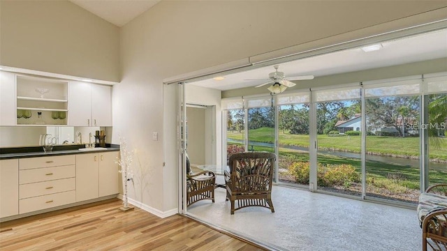 interior space with a ceiling fan, open shelves, dark countertops, white cabinets, and light wood finished floors