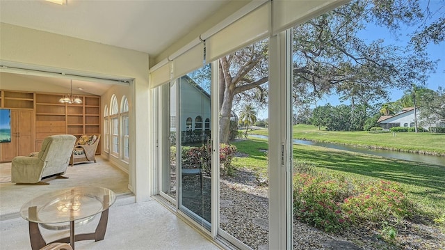 sunroom with lofted ceiling, a notable chandelier, and a water view