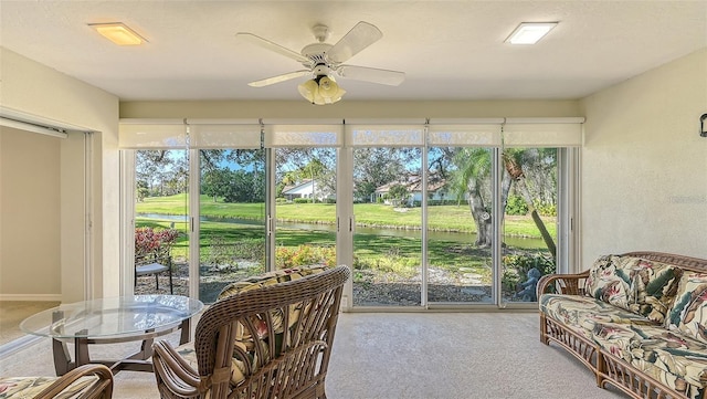 sunroom featuring a water view and ceiling fan