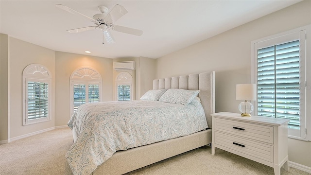 bedroom featuring light carpet, ceiling fan, baseboards, and a wall unit AC