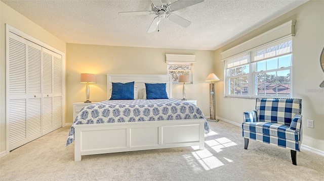 bedroom with a ceiling fan, baseboards, a closet, and light carpet