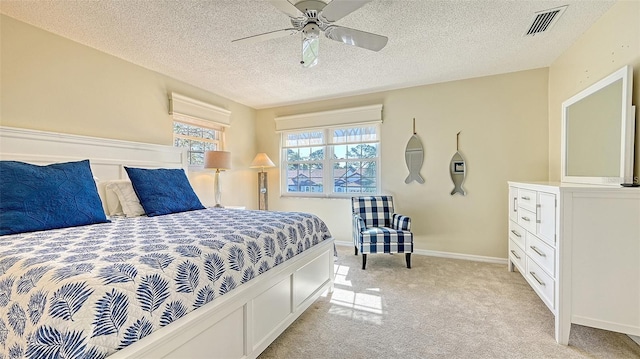 bedroom featuring a textured ceiling, light colored carpet, visible vents, and baseboards