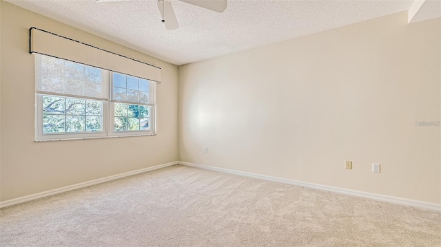 spare room with a textured ceiling, carpet, baseboards, and ceiling fan