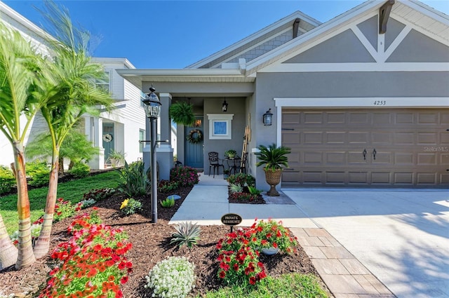 view of front facade with stucco siding, a garage, covered porch, and driveway