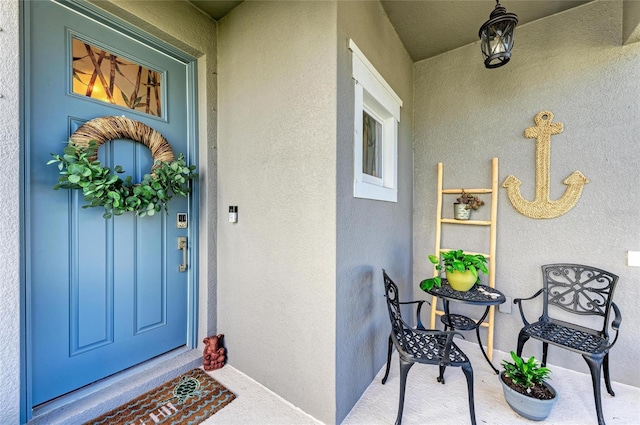 entrance to property featuring a porch and stucco siding