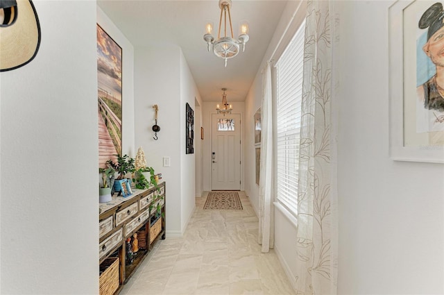 hallway featuring a notable chandelier and baseboards