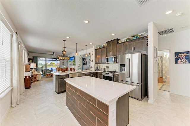 kitchen featuring visible vents, dark brown cabinetry, light countertops, a peninsula, and stainless steel appliances