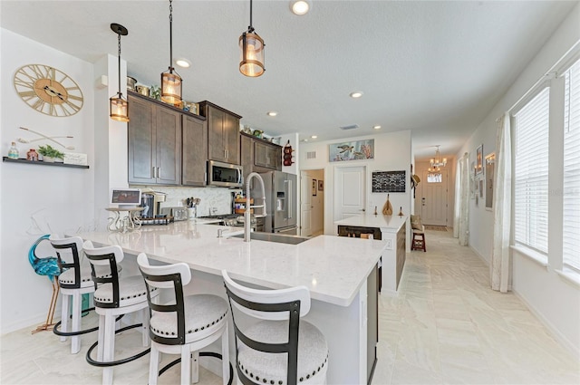 kitchen featuring tasteful backsplash, dark brown cabinets, appliances with stainless steel finishes, and a peninsula