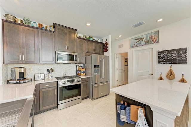 kitchen featuring stainless steel appliances, dark brown cabinetry, visible vents, and decorative backsplash