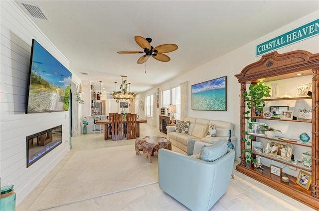 living room featuring visible vents, a large fireplace, and ceiling fan with notable chandelier