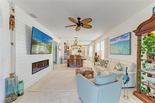 living area with a fireplace, ceiling fan with notable chandelier, visible vents, and carpet floors