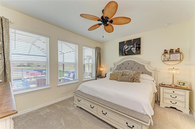 bedroom with a ceiling fan, light colored carpet, and baseboards