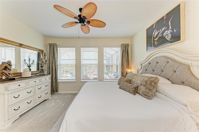 bedroom with light colored carpet, baseboards, a ceiling fan, and multiple windows