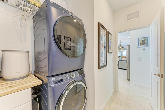 laundry room with laundry area, visible vents, stacked washer and clothes dryer, and baseboards