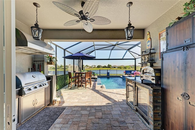 view of patio with a lanai, grilling area, a ceiling fan, and an outdoor kitchen