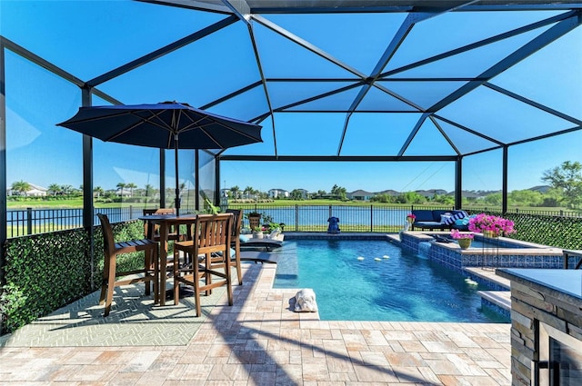 view of swimming pool with glass enclosure, a pool with connected hot tub, a patio, and fence