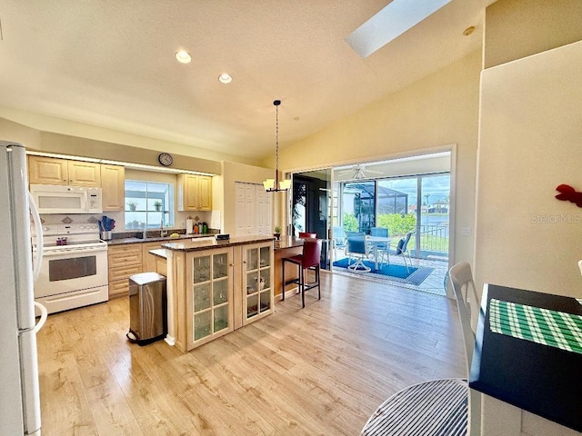 kitchen with white appliances, plenty of natural light, lofted ceiling with skylight, and light brown cabinetry