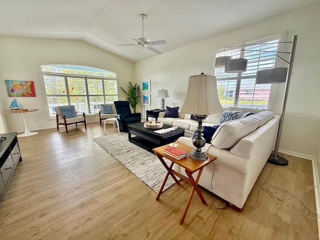 living room featuring baseboards, light wood-type flooring, a ceiling fan, and vaulted ceiling