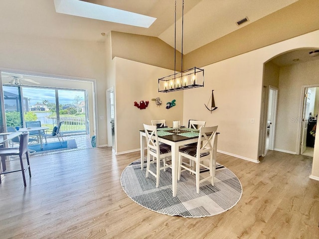 dining room featuring visible vents, arched walkways, light wood-style floors, and vaulted ceiling