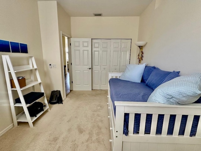 bedroom with a closet, visible vents, light colored carpet, and baseboards