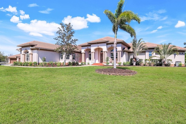 mediterranean / spanish-style house with stucco siding, a tile roof, and a front yard