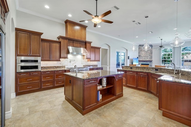 kitchen featuring a ceiling fan, a sink, a large island, under cabinet range hood, and stainless steel oven