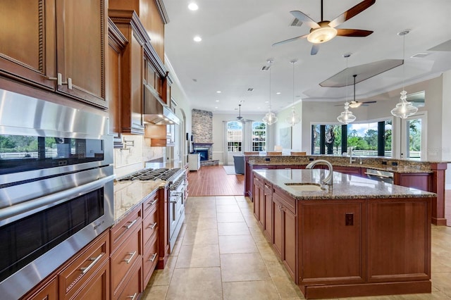 kitchen featuring a spacious island, backsplash, appliances with stainless steel finishes, a ceiling fan, and a sink