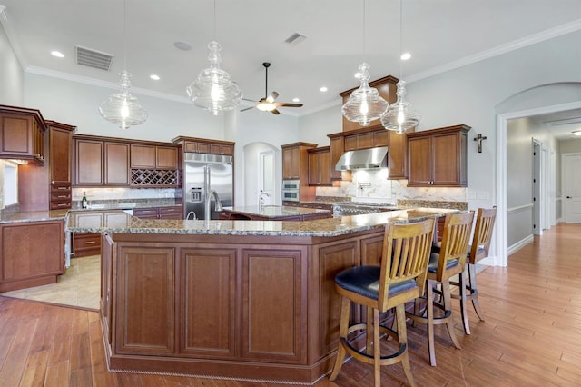 kitchen featuring visible vents, ceiling fan, under cabinet range hood, appliances with stainless steel finishes, and arched walkways