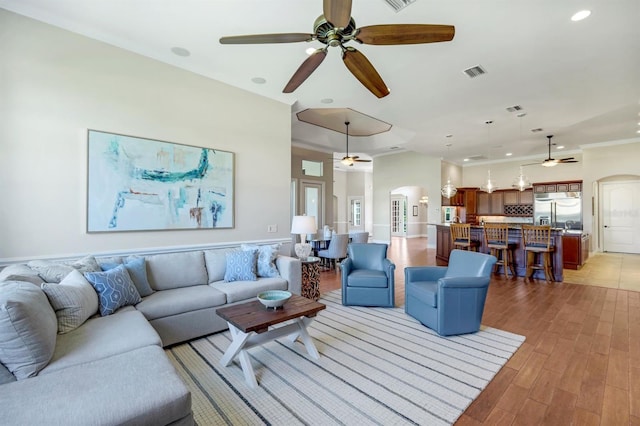 living area with visible vents, recessed lighting, arched walkways, ceiling fan, and light wood-type flooring