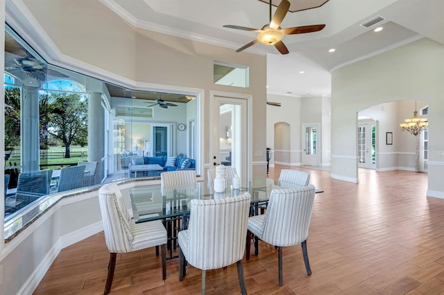 dining space with visible vents, ornamental molding, ceiling fan with notable chandelier, wood finished floors, and arched walkways