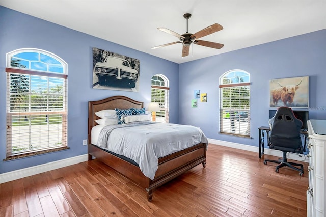 bedroom with baseboards, multiple windows, wood finished floors, and a ceiling fan