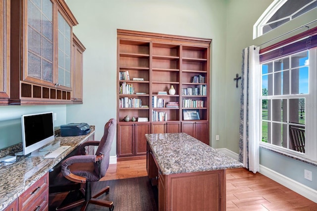 office area with light wood-type flooring, baseboards, and built in study area