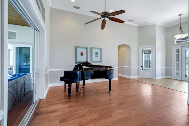 foyer with visible vents, arched walkways, a high ceiling, and light wood finished floors