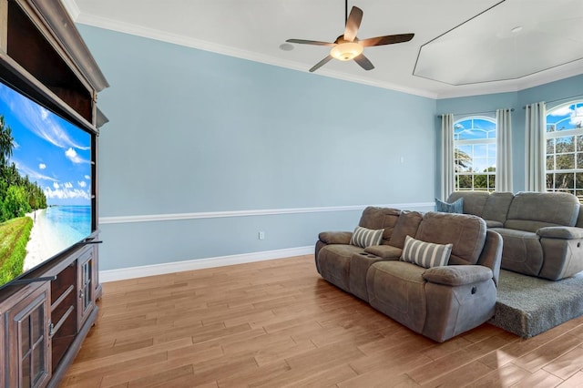 living area featuring a ceiling fan, baseboards, light wood finished floors, and ornamental molding