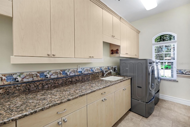 laundry area featuring a sink, baseboards, light tile patterned flooring, cabinet space, and separate washer and dryer