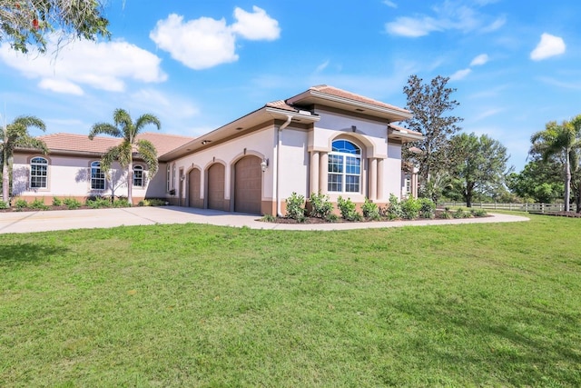 mediterranean / spanish-style home featuring concrete driveway, a front lawn, a garage, and stucco siding