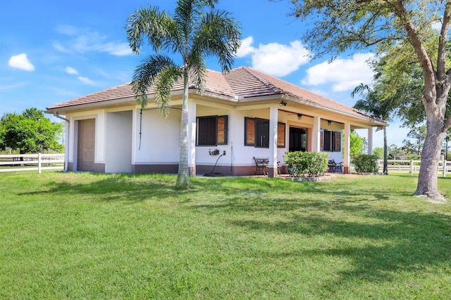 rear view of property with a tiled roof, a yard, an attached garage, and fence