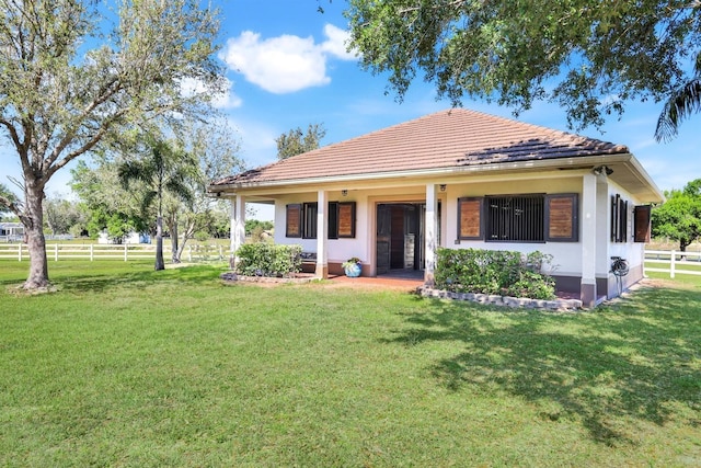 back of property with a tile roof, a yard, fence, and stucco siding