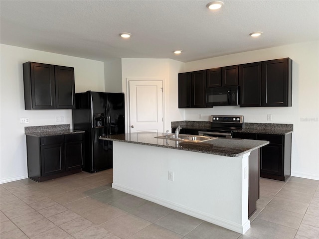 kitchen featuring black appliances, dark stone countertops, a kitchen island with sink, and a sink