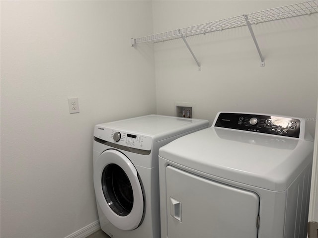 washroom featuring washing machine and clothes dryer, laundry area, and baseboards