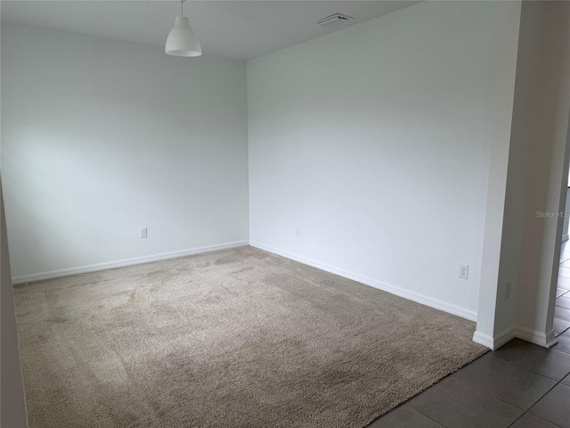 carpeted spare room with visible vents and baseboards