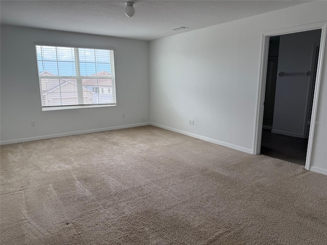 unfurnished bedroom featuring a walk in closet, carpet flooring, baseboards, and a textured ceiling