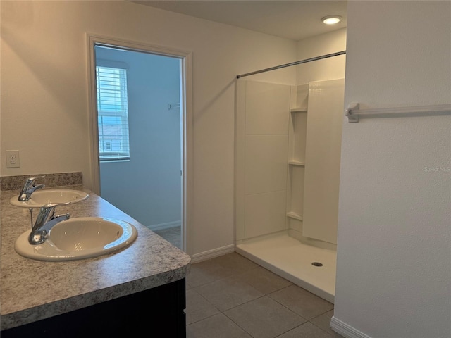 full bathroom with tile patterned floors, double vanity, walk in shower, and a sink