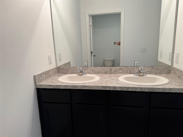 bathroom with double vanity, toilet, and a sink