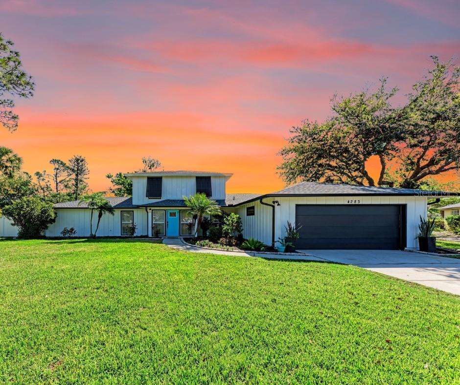 traditional-style home featuring a lawn, a garage, and driveway