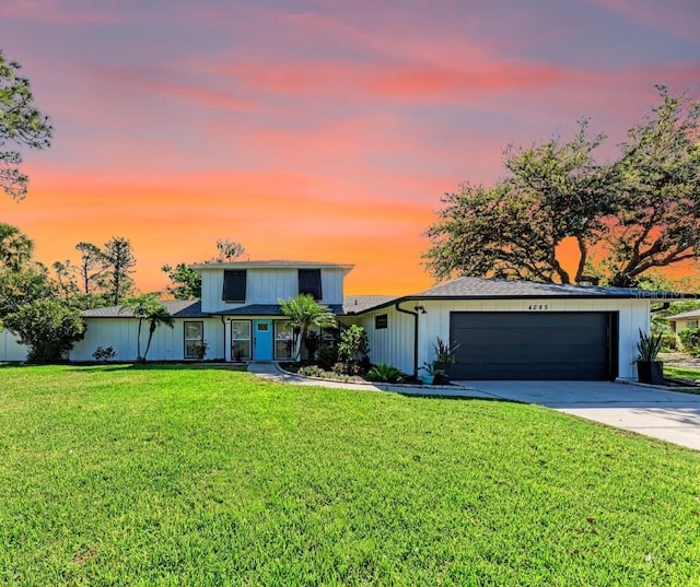 traditional-style home featuring a lawn, a garage, and driveway