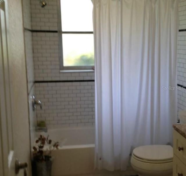 full bath featuring toilet, vanity, and shower / bath combo