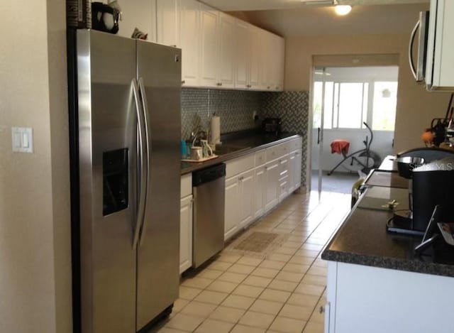 kitchen with tasteful backsplash, dark countertops, white cabinetry, stainless steel appliances, and light tile patterned floors