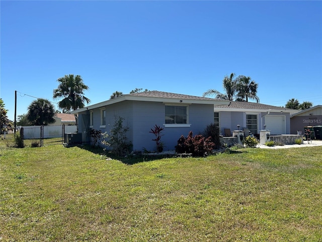 rear view of property featuring a lawn, a garage, and fence